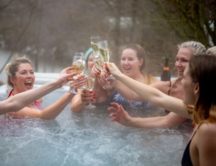 A group of people sitting in the hot tub drinking wine.