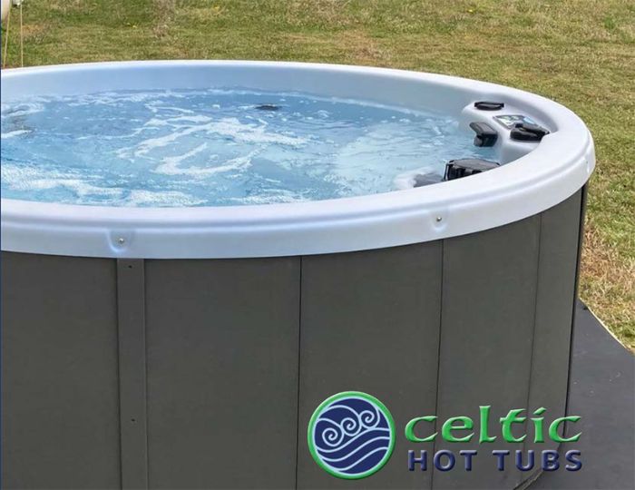 A hot tub with the lid up and grass in the background.